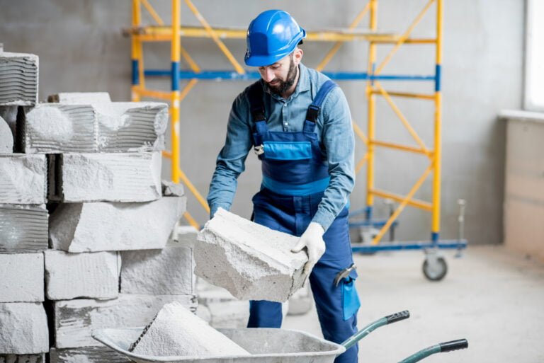 Builder in uniform working with building blocks at the construction site